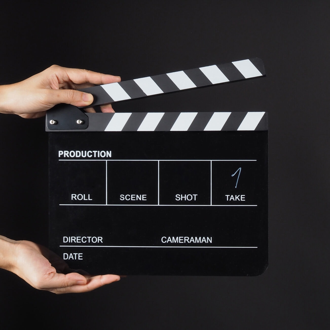Hand is holding Black clap board or movie slate  use in video production , movie ,film, cinema industry on black background.It have write in number.